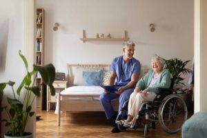 A caregiver helping an older adult with mobility exercises in a comfortable residential setting.